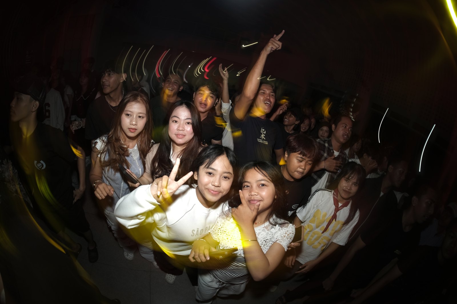 Penonton Liveverse berkumpul di depan panggung dalam cahaya kuning.