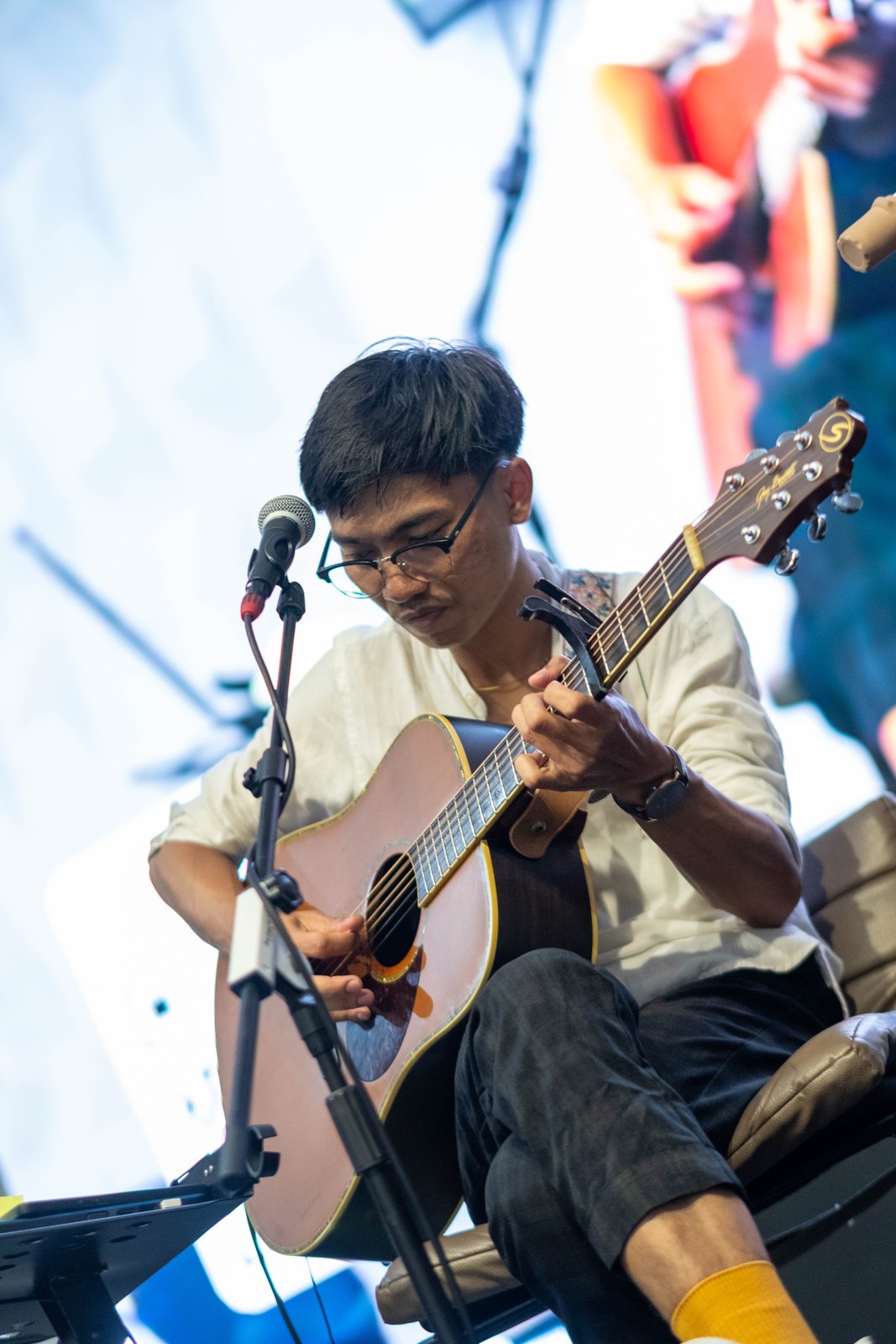 Gitaris Soulcoustic memainkan gitar akustik di depan mikrofon.